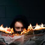 Elinde yanan bir gazete tutan bir kadın.