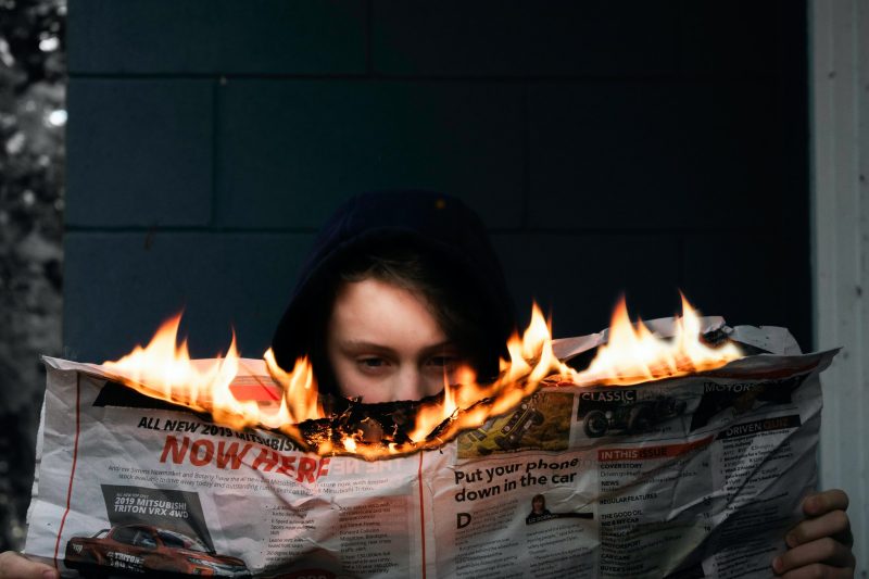 Elinde yanan bir gazete tutan bir kadın.