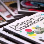 Delayed Gratification dergisinin farklı sayıları bir masa üzerine dizilmiş.