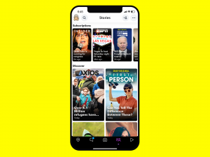 Sarı arka plan üzerinde bir iPhone, ekranında Snapchat'in dinamik hikayelerinin örnekleri görülüyor.