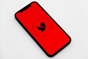 Telefon ekranında kırmızı üzerine siyahla Twitter logosu ve üzerinde yasaktır işareti.