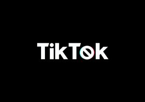 Siyah üzerine beyaz yazıyla TikTok yazıyor, ancak o harfi yasaklama sembolü gibi ve etrafında TikTok logosuna benzer renkli dalgalar var.