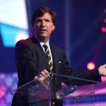 Tucker Carlson'ın bir etkinlikte kürsüde konuşurken çekilmiş bir fotoğrafı.