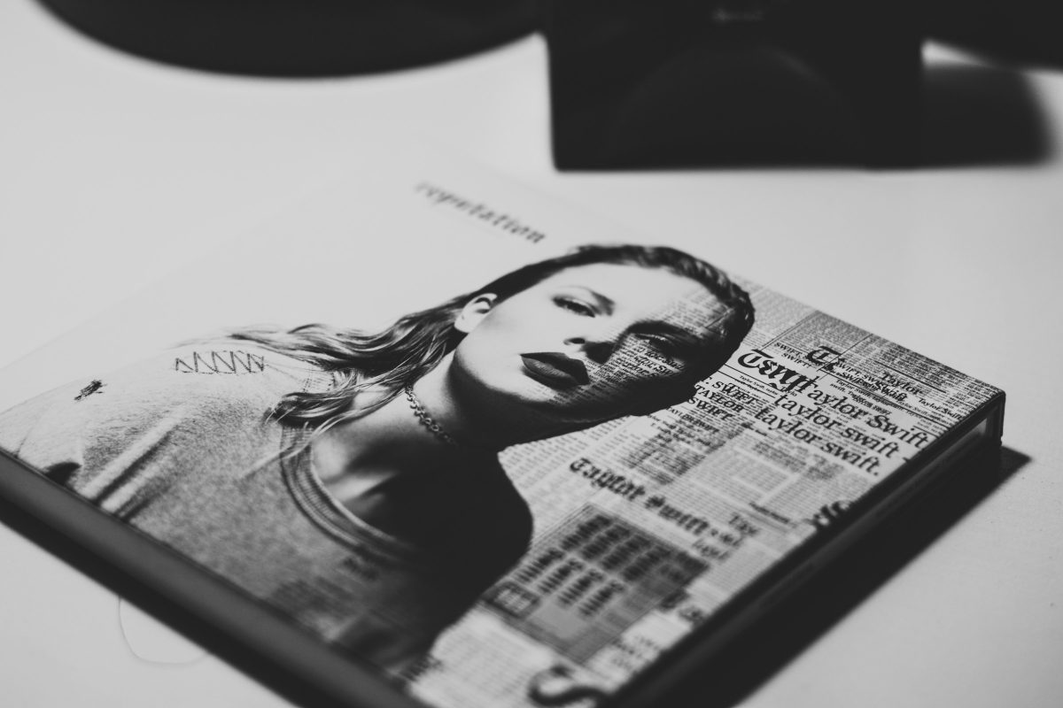 Gazete küpürleri ve Taylor Swift'in bir fotoğrafıyla oluşturulmuş kolaj bir tablonun masa üstünde dururken çekilmiş siyah beyaz fotoğrafı.