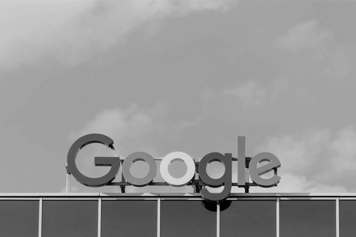 Siyah beyaz fotoğrafta bir binanın çatısındaki Google logosu var.