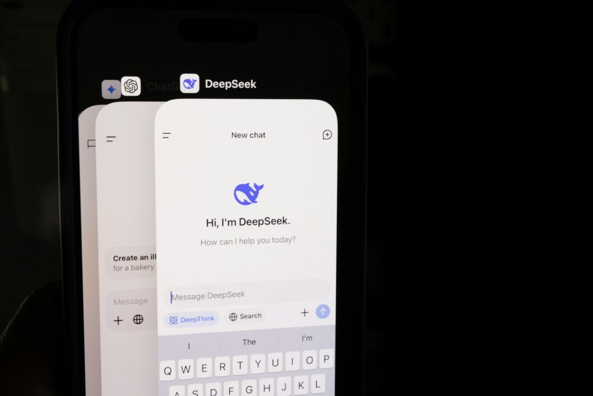 Bir telefonun siyah bir arka plan üzerinde fotoğrafı. Ekranında en önde DeepSeek uygulaması, arkasında ChatGPT ve Gemini uygulamaları görülüyor.